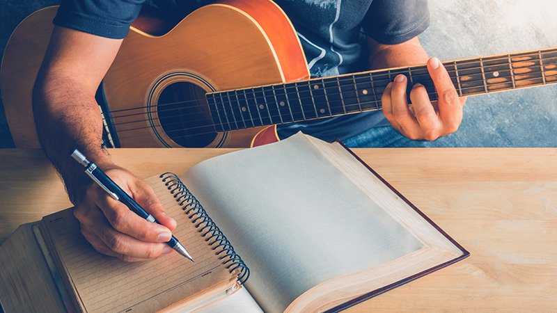 Hombre componiendo con una guitarra y un cuaderno