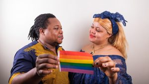 hombre y mujer sosteniendo en conjunto una bandera con el arcoiris