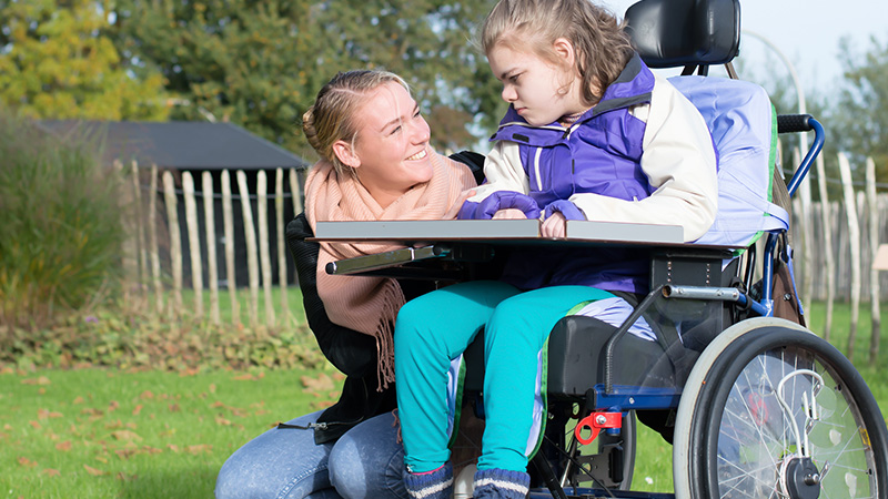 Madre acompaña y anima a su hija en silla de ruedas