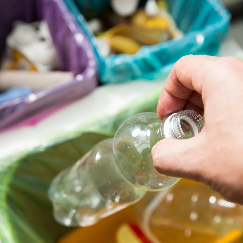 depositando botella plastica en contenedor clasificado