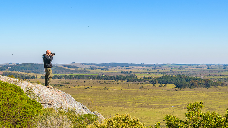 vista panorámica desde la altura de un cerro con una persona tomando una foto parada en una roca