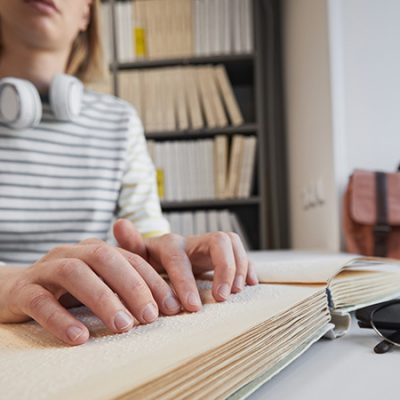 mujer no vidente leyendo un texto de braille en una biblioteca